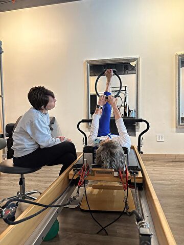 pilates instructor guides a client through an exercise at cor studio