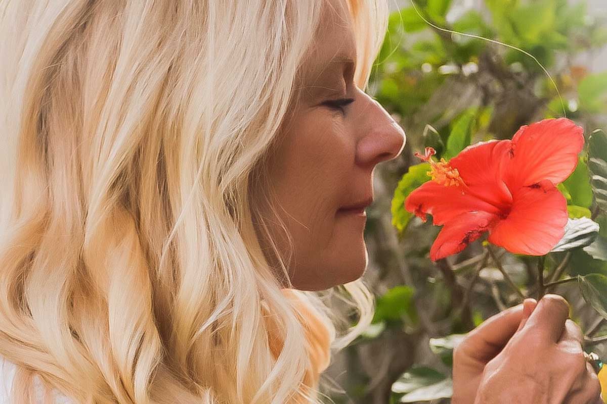 diane of destiny wellness smelling a pink flower