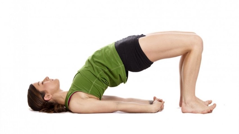 postpartum woman doing a bridge yoga pose at cocoon care