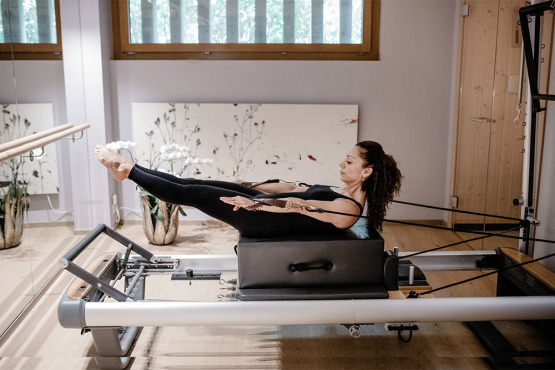 Woman doing ab workout on pilates machine at Enforme