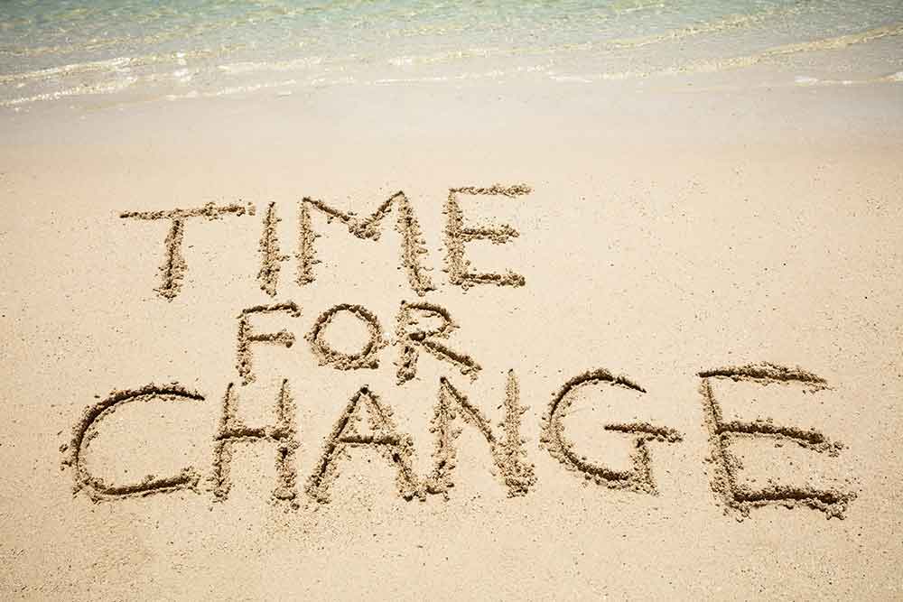 beach with the words time for change written in the sand