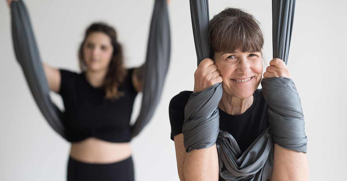 woman smiling in an aerial yoga class at honor yoga