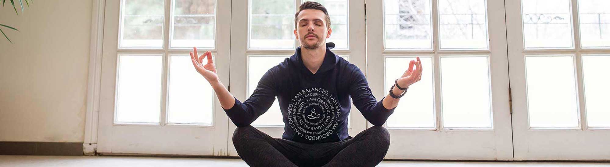 man in lotus position at home with honor yoga