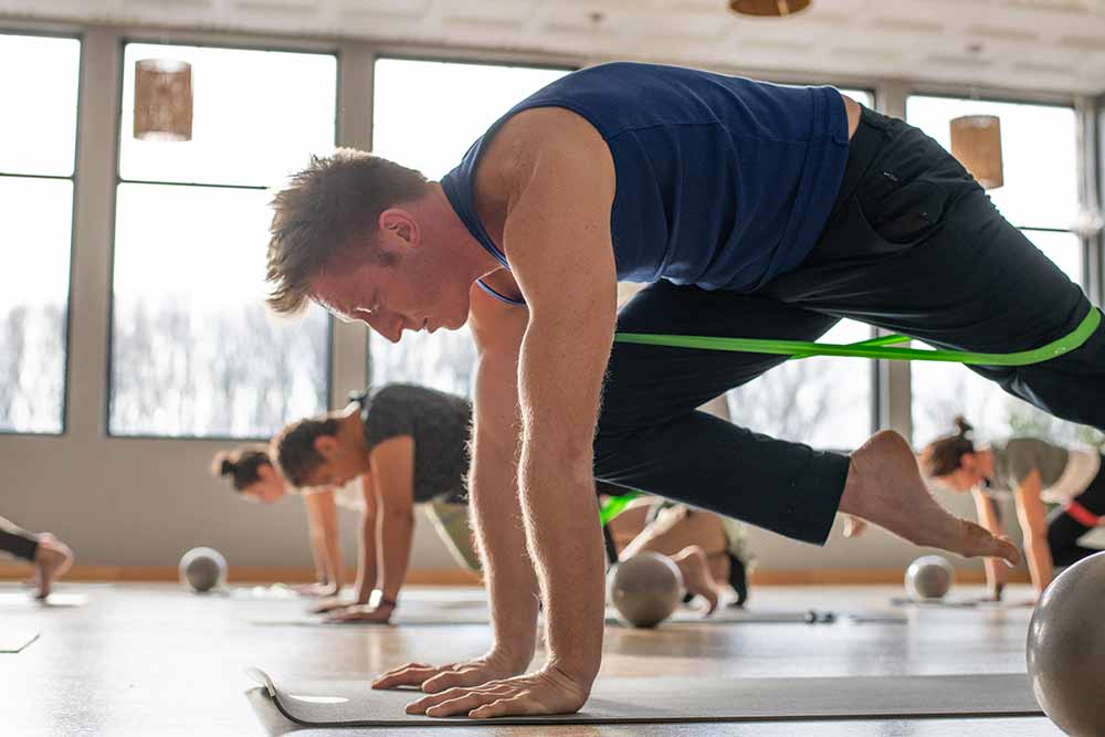 man using resistance bands in a yoga class at honor yoga