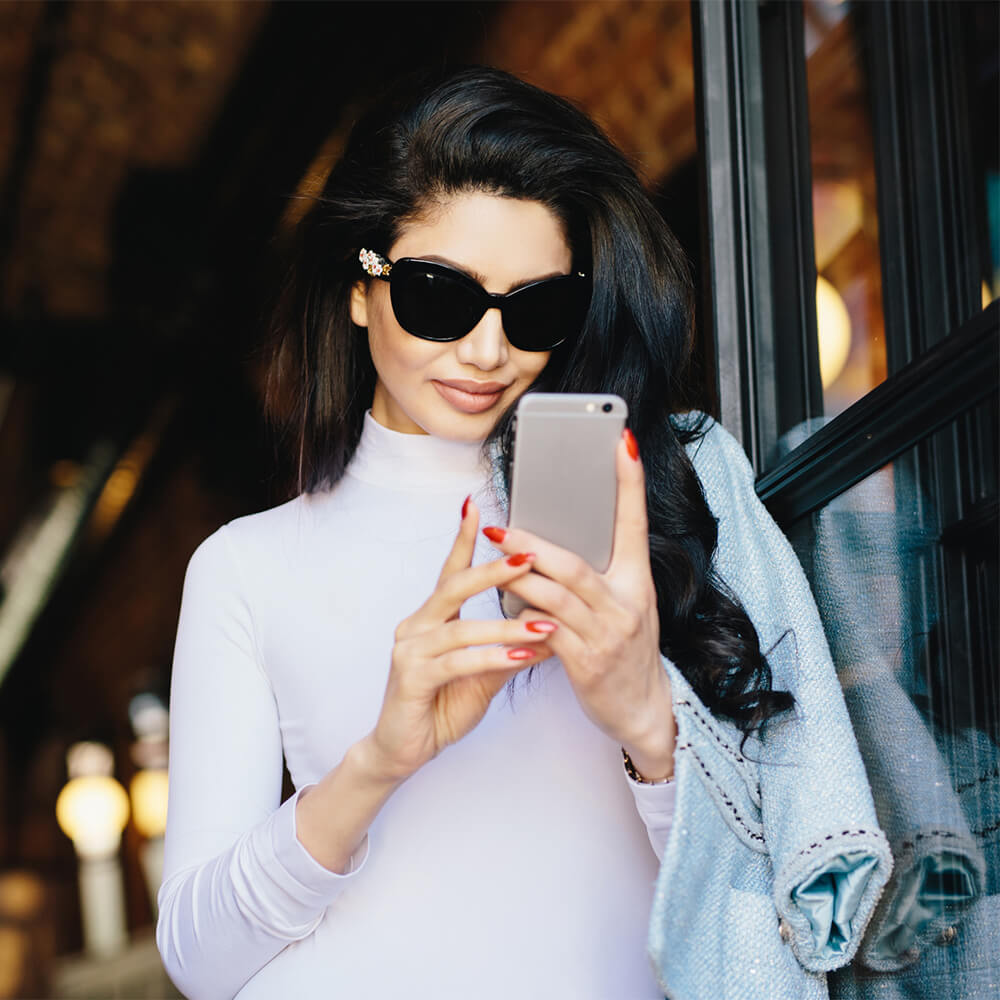 woman with big sunglasses looking at cellphone