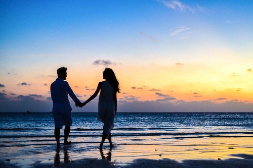 couple walking on the beach at sunset - living a long healthy life