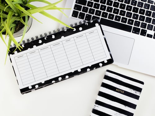 daily planner sitting next to a laptop