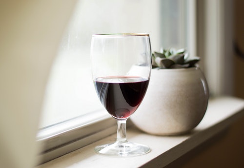 glass of red wine sitting by the window