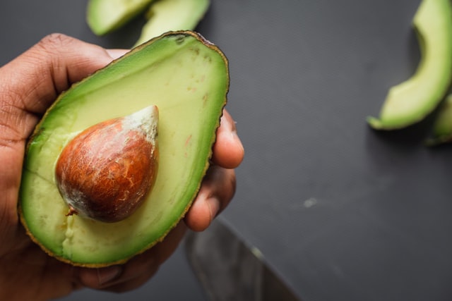 hand showing half an avocado - healthy fat superfood