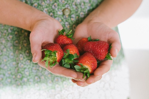person holding strawberries in their hand - what is organic