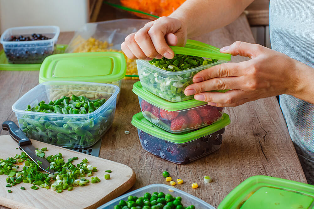 woman prepping vegetables into plastic containers in leora's kitchen