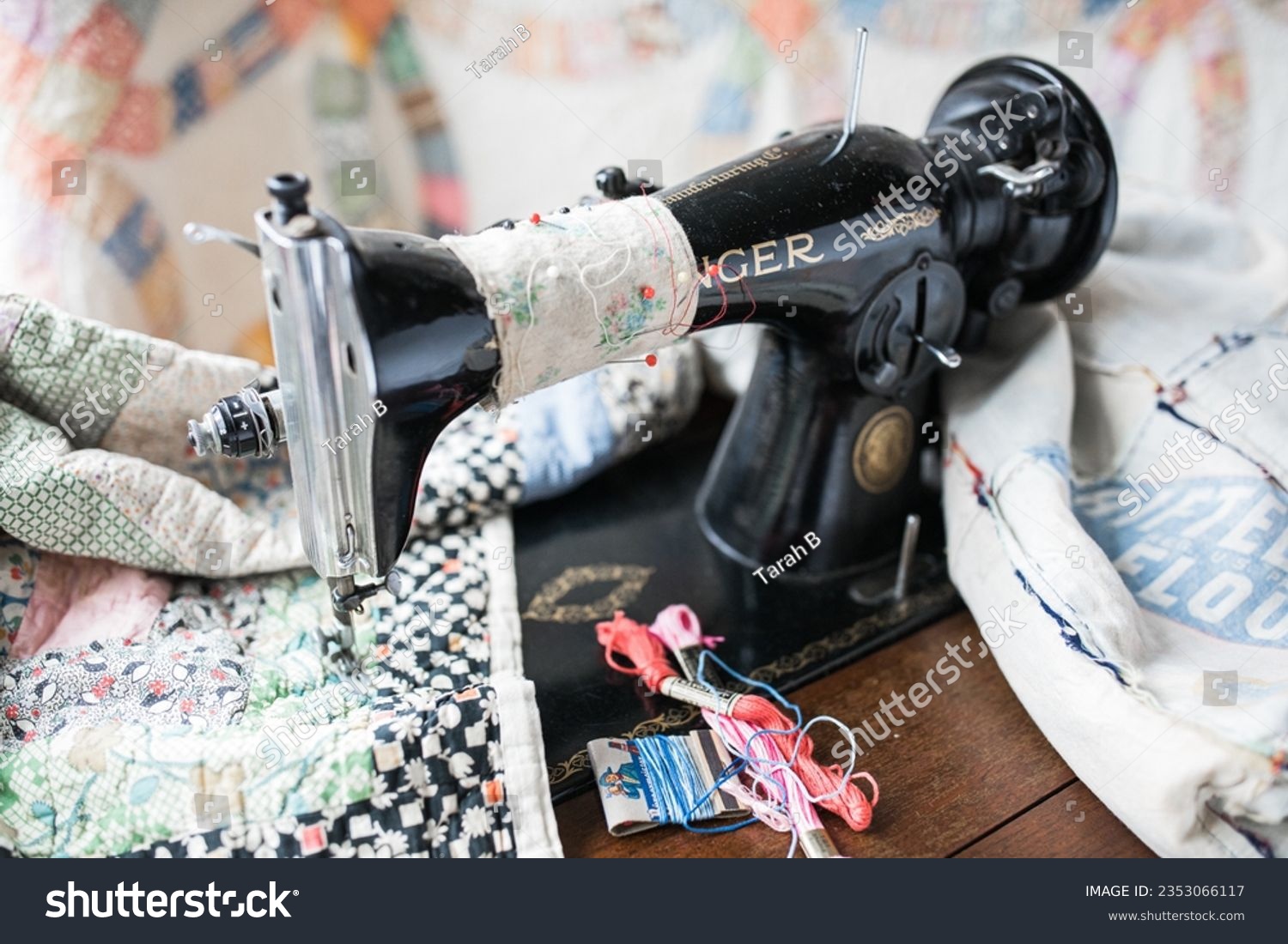 stock-photo-antique-black-sewing-machine-making-large-quilt-with-needles-in-cloth-2353066117