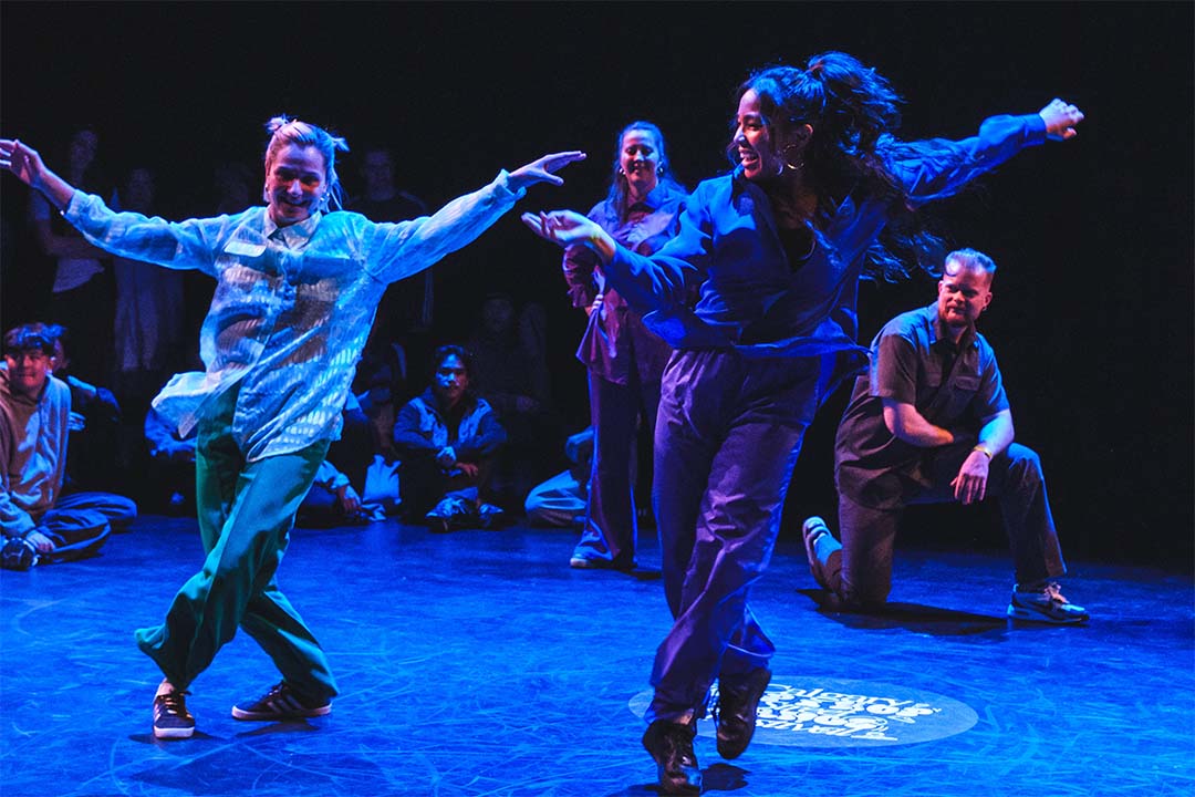 Two energetic dancers performing Hip Hop moves on stage, surrounded by an engaged Calgary Hip Hop and Streetdance audience. Perfect representation of high-intensity Hip Hop dance classes that combine fun, fitness, and creativity to achieve New Year fitness goals.