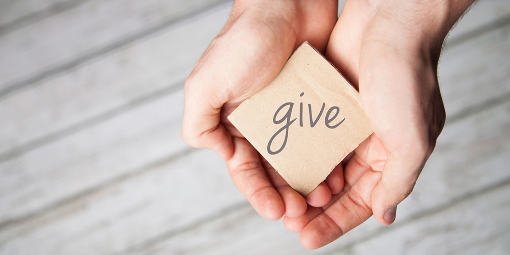 woman holding a note that says give on it