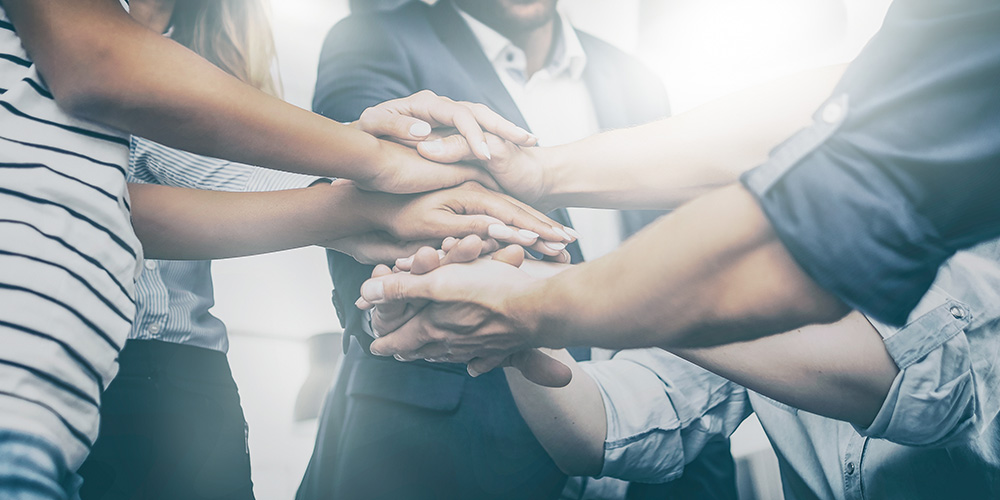 group of people surrounding their overlapping hands