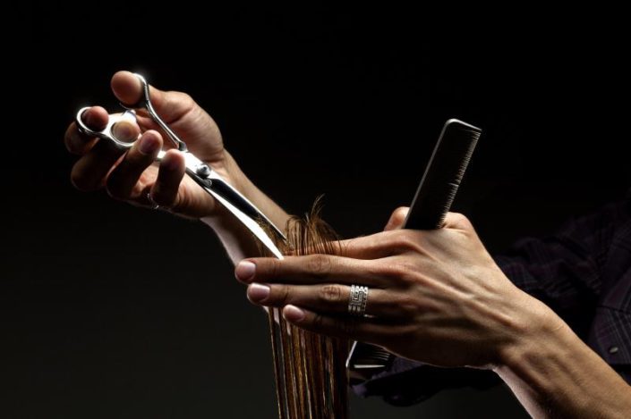 a close up of hairdressers hands cutting hair