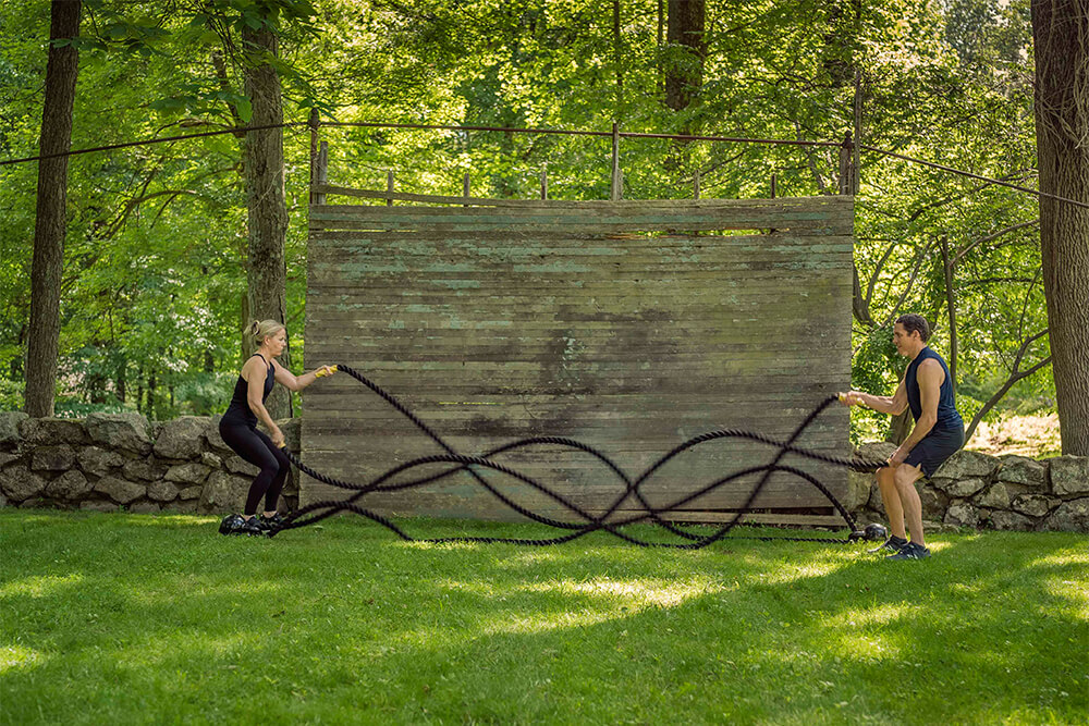 2 people in an outdoor hiit class using ropes at ride + reflect