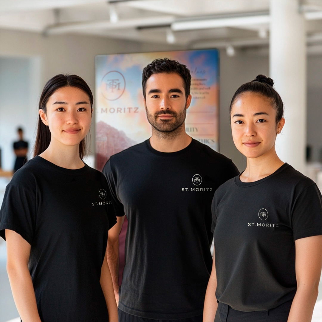 Group of three St Moritz staff standing Infront of a poster